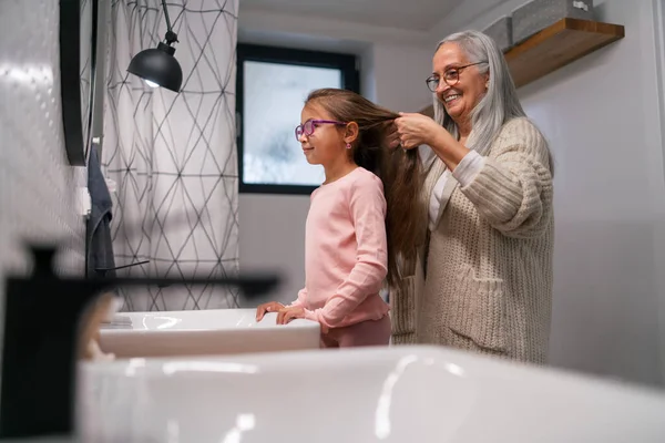 Abuela mayor y nieta de pie en el interior en el baño, concepto de rutina diaria. — Foto de Stock