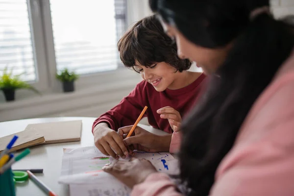 Little multiracial boy doing homework with his mother at home. — Stock Photo, Image