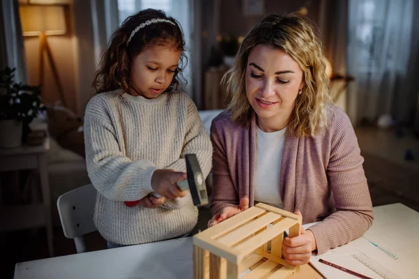 Happy little girl renovating a wooden crate together with her mother at home. — Stock Photo, Image