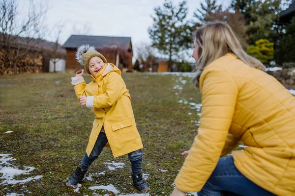 Annesi bahçede karla oynarken Down sendromlu bir çocuk.. — Stok fotoğraf