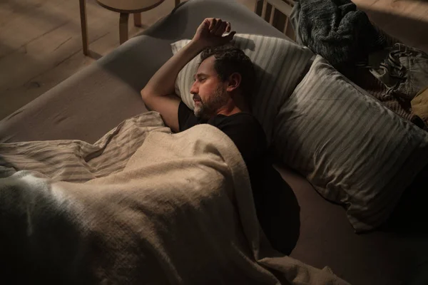 Droevige volwassen man die lijdt aan hevige depressie liggend in bed in de nacht. — Stockfoto
