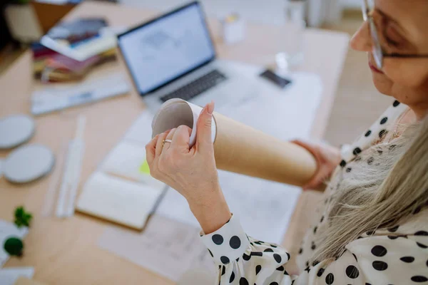 Close-up of woman architect pulling rolled-up blueprints out of tube in office. — Stock Photo, Image