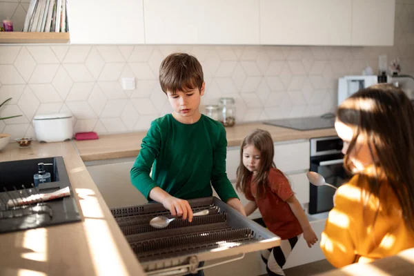 Tre piccoli chidlren che aiutano con i piatti in cucina a casa. — Foto Stock