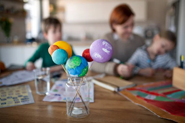 Madre de niños pequeños que los supervisan cuando hacen la tarea en casa. — Foto de Stock