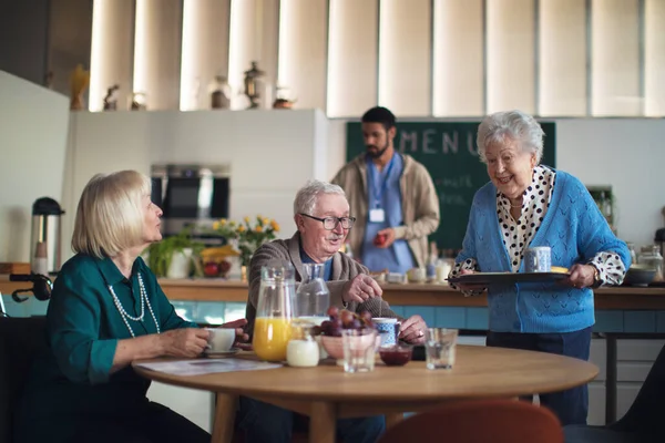 En grupp glada seniorer njuter av frukosten på vårdhemmet. — Stockfoto