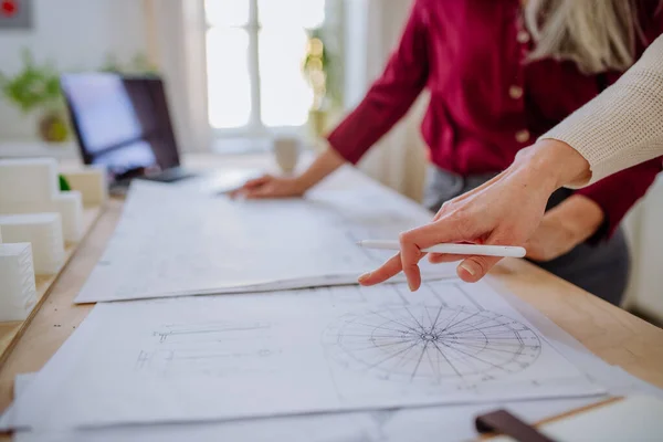 Närbild av mogna kvinnliga arkitekter som tittar på ritningar tillsammans på kontoret . — Stockfoto