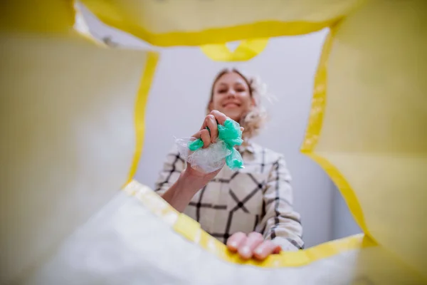 Obraz z wnętrza żółtej torby na recykling kobiety rzucającej tworzywa sztuczne do recyklingu. — Zdjęcie stockowe