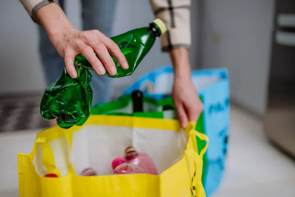 Onherkenbare vrouw gooit lege plastic fles in de prullenbak in de keuken. — Stockfoto