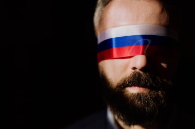 Siyah arka planda Rus bayrağı olan bir adam, Rus propagandası kapalı gözler kavramı.
