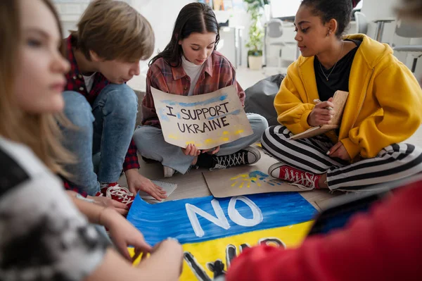 Estudiantes adolescentes sentados en círculo en el aula con carteles para apoyar a Ucrania, sin concepto de guerra. —  Fotos de Stock