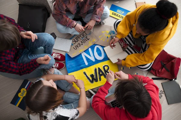 Ansicht von Teenagern, die im Klassenzimmer im Kreis sitzen, mit Postern zur Unterstützung der Ukraine, kein Kriegskonzept. — Stockfoto