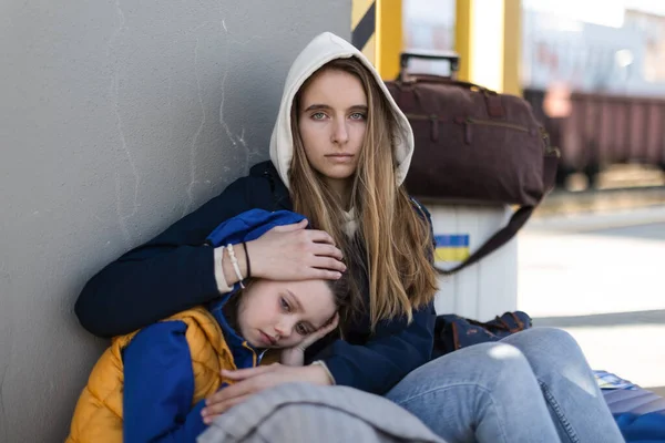 Depressed Ukrainian immigrants sitting and waiting at railway station.