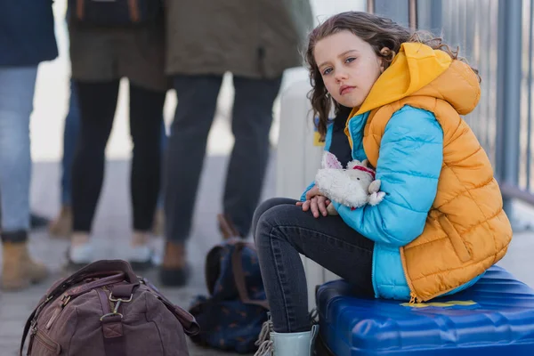 Trauriges ukrainisches Einwandererkind mit am Bahnhof wartendem Gepäck, ukrainisches Kriegskonzept. — Stockfoto