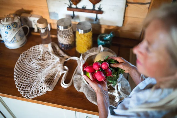 Gros plan de la femme âgée méconnaissable déballer des achats à l'intérieur à la maison, mode de vie durable. — Photo