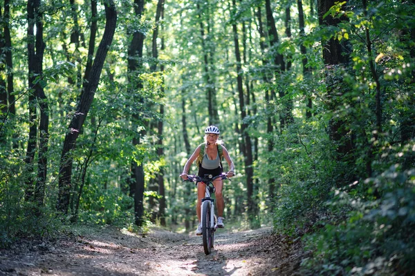 जंगलात बाहेर सक्रिय वरिष्ठ महिला बाइकर सायकलिंगचे समोर दृश्य . — स्टॉक फोटो, इमेज
