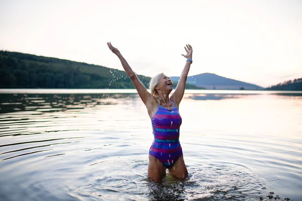 Portret aktywnej starszej kobiety pływającej stojącej i rozciągającej się na świeżym powietrzu w jeziorze. — Zdjęcie stockowe