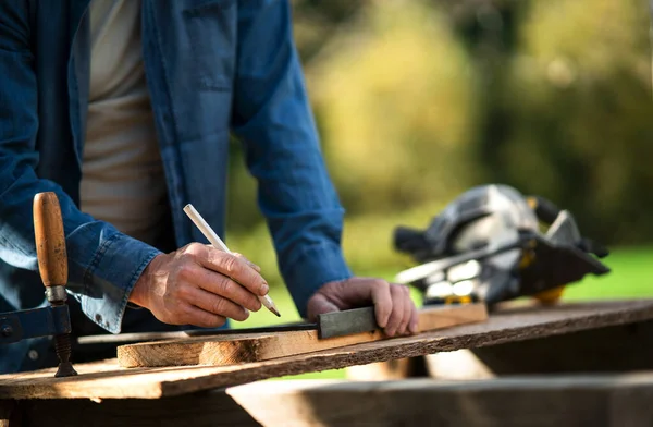 Close-up of handyman measuring a board, outside in garden. — Stock Photo, Image