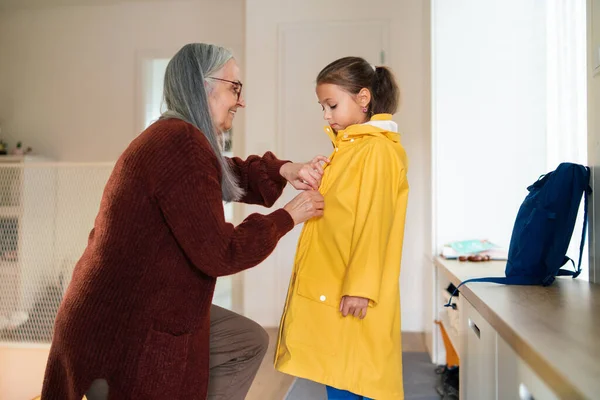 Grandmother helping granddaughter to get ready to leave home for school. — Stock Photo, Image