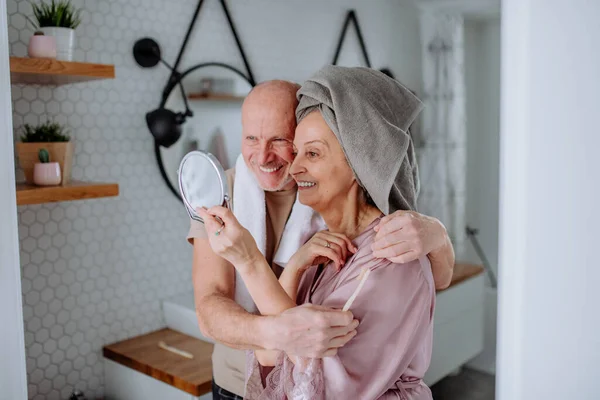 Idős pár szerelmes a fürdőszobában, nézi tükör és mosolygós, reggeli rutin koncepció. — Stock Fotó