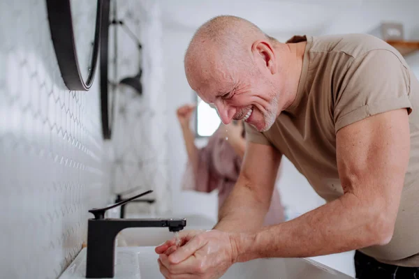 Coppia anziana in bagno, lavarsi i denti e lavarsi, concetto di routine mattutina. — Foto Stock