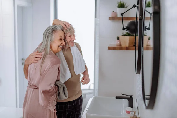 Ηλικιωμένο ζευγάρι ερωτευμένο στο μπάνιο, κοιτάζεται στον καθρέφτη και διασκεδάζει, το πρωί έννοια ρουτίνας. — Φωτογραφία Αρχείου