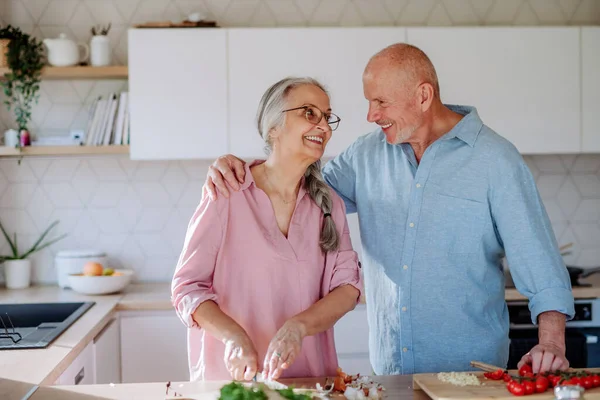 Счастливая пожилая пара готовит вместе дома. — стоковое фото