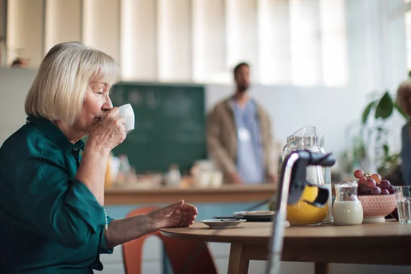 Glimlachende oudere vrouw genieten van ontbijt in verpleeghuis zorgcentrum. — Stockfoto