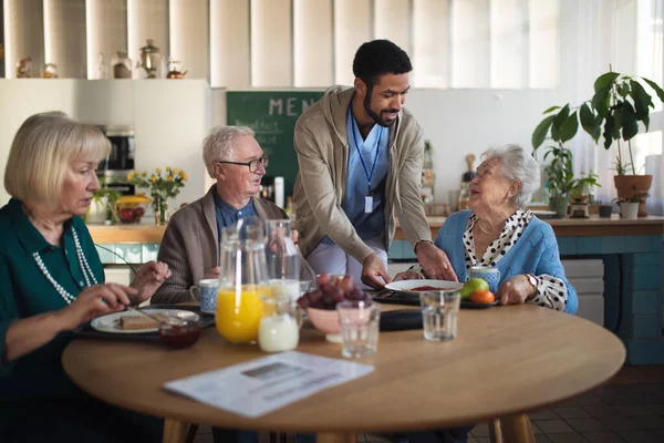 En grupp glada seniorer njuter av frukosten på vårdhemmet. — Stockfoto