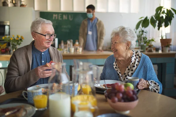 Sorridente donna anziana e uomo godendo la colazione nel centro di assistenza domiciliare. — Foto Stock