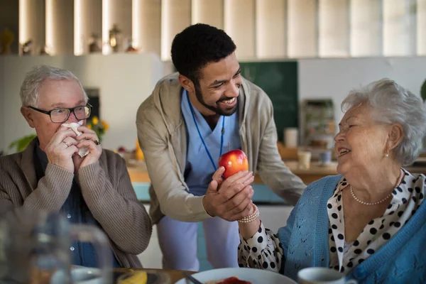 Leende äldre kvinna och man njuter av frukost på vårdhemmet. — Stockfoto