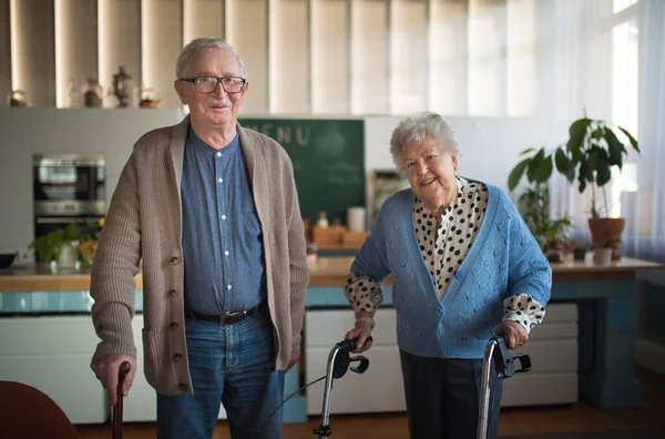Senior man och kvinna promenader med vandrare inomhus i pension omvårdnad hme. — Stockfoto