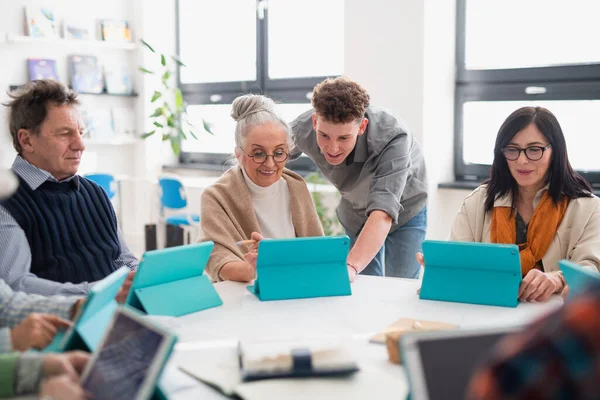 Gruppo di anziani che frequentano il corso di informatica nel centro sociale con insegnante — Foto Stock