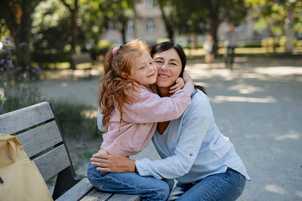 Feliz niña abrazando a su abuela al aire libre en el parque. — Foto de Stock