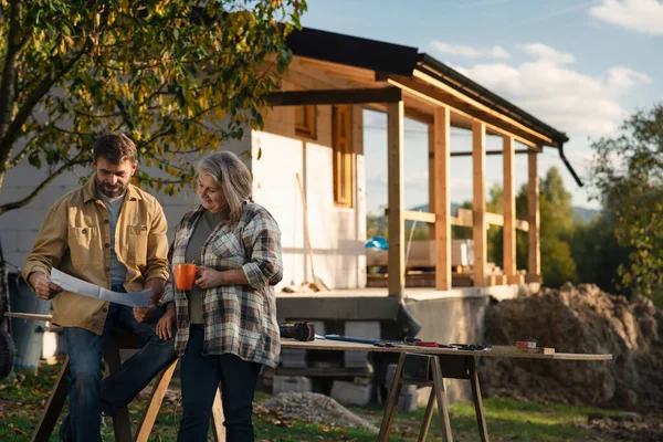Mature couple having coffee break when working together on construction site of their new house. — Stock Photo, Image
