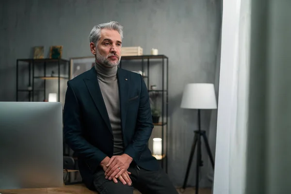 Volwassen trieste zakenman zit op het bureau en denken binnen in het kantoor. — Stockfoto