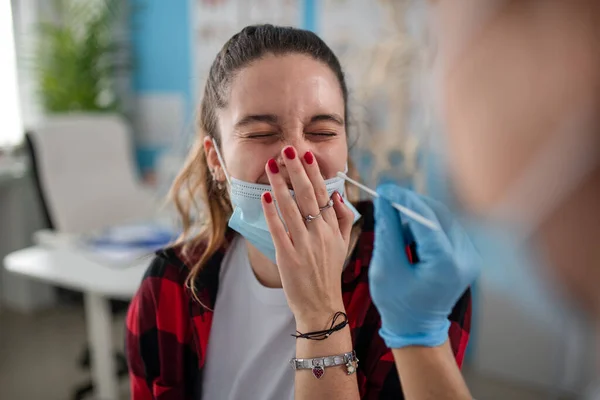 Lékař přičemž nosní stěr test od mladé ženy na klinice. — Stock fotografie