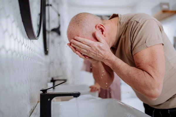 Casal sênior no banheiro, rosto de lavagem, conceito de rotina matinal. — Fotografia de Stock