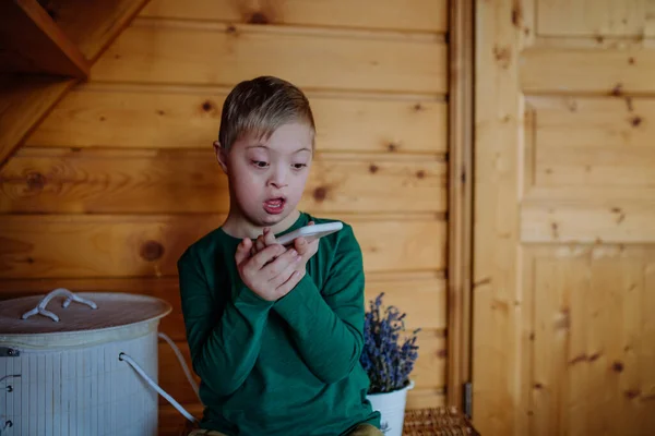Überraschter kleiner Junge mit Down-Syndrom nutzt Smartphone zu Hause — Stockfoto