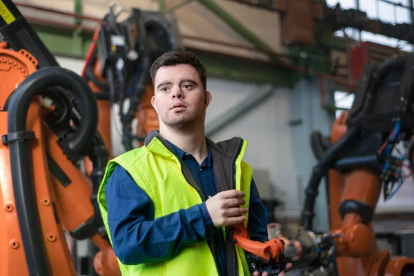 Young man with Down syndrome working in industrial factory, social integration concept. — Stock Photo, Image