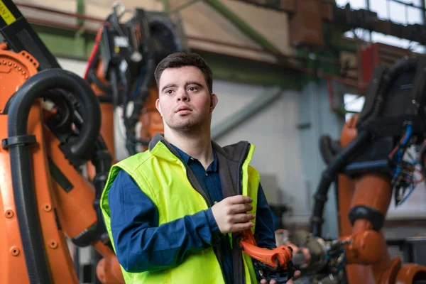 Joven con síndrome de Down trabajando en fábrica industrial, concepto de integración social. — Foto de Stock