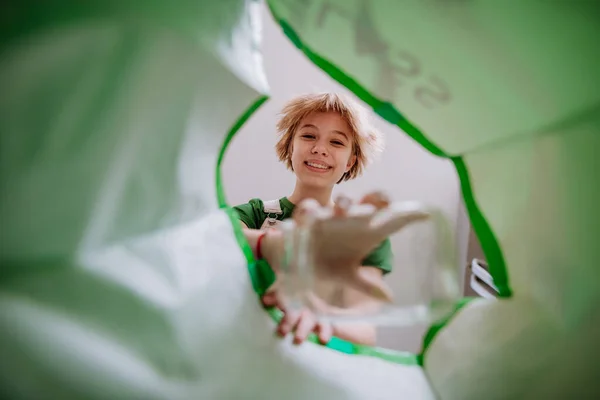 Bild från insidan grön återvinning påse med flicka kasta en glasflaska för att återvinna. — Stockfoto