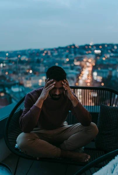 Retrato od deprimido joven afroamericano con la cabeza en las manos sentado en el balcón por la noche. — Foto de Stock