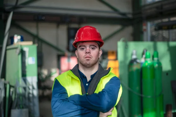 Young man with Down syndrome working in industrial factory, social integration concept. — Stock Photo, Image