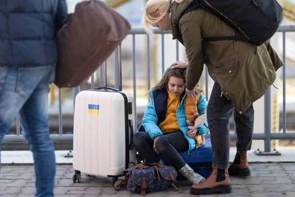 Traurige ukrainische Einwanderer mit am Bahnhof wartendem Gepäck, ukrainisches Kriegskonzept. — Stockfoto