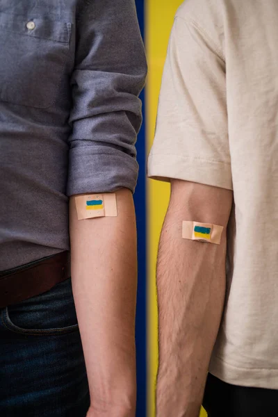 Donneurs de sang avec bandage après avoir donné du sang sur fond drapeau ukrainien. — Photo