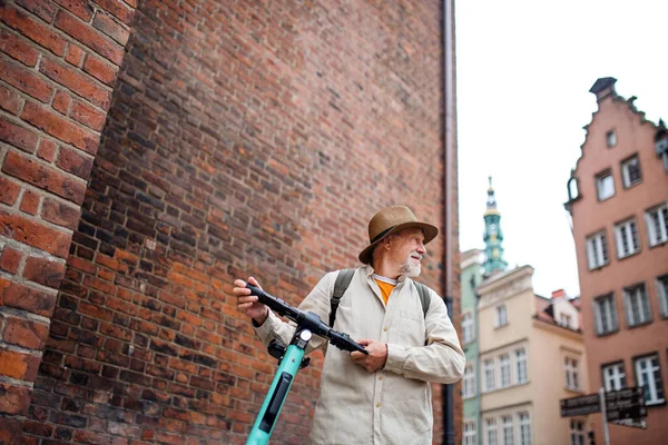 Ritratto di felice anziano uomo turista equitazione scooter all'aperto in città — Foto Stock
