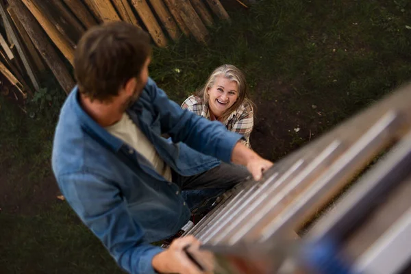 High angle view of mature man climbing up the ladder looking at his wife — Stock Photo, Image