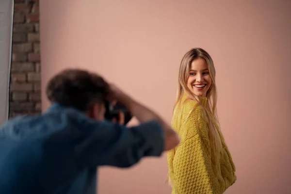 Joven fotógrafo tomando fotos de modelo, tras bastidores de fotografía en estudio. —  Fotos de Stock