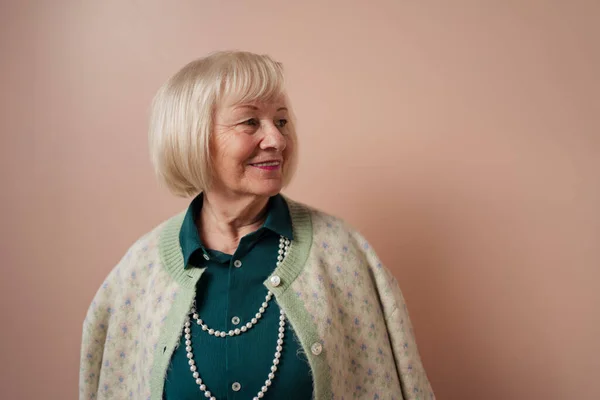 Glimlachende elegante oudere vrouw op roze kleur achtergrond, studio portret — Stockfoto