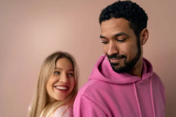 Retrato de estúdio de moda de um jovem casal feliz com capuz posando sobre fundo rosa. — Fotografia de Stock